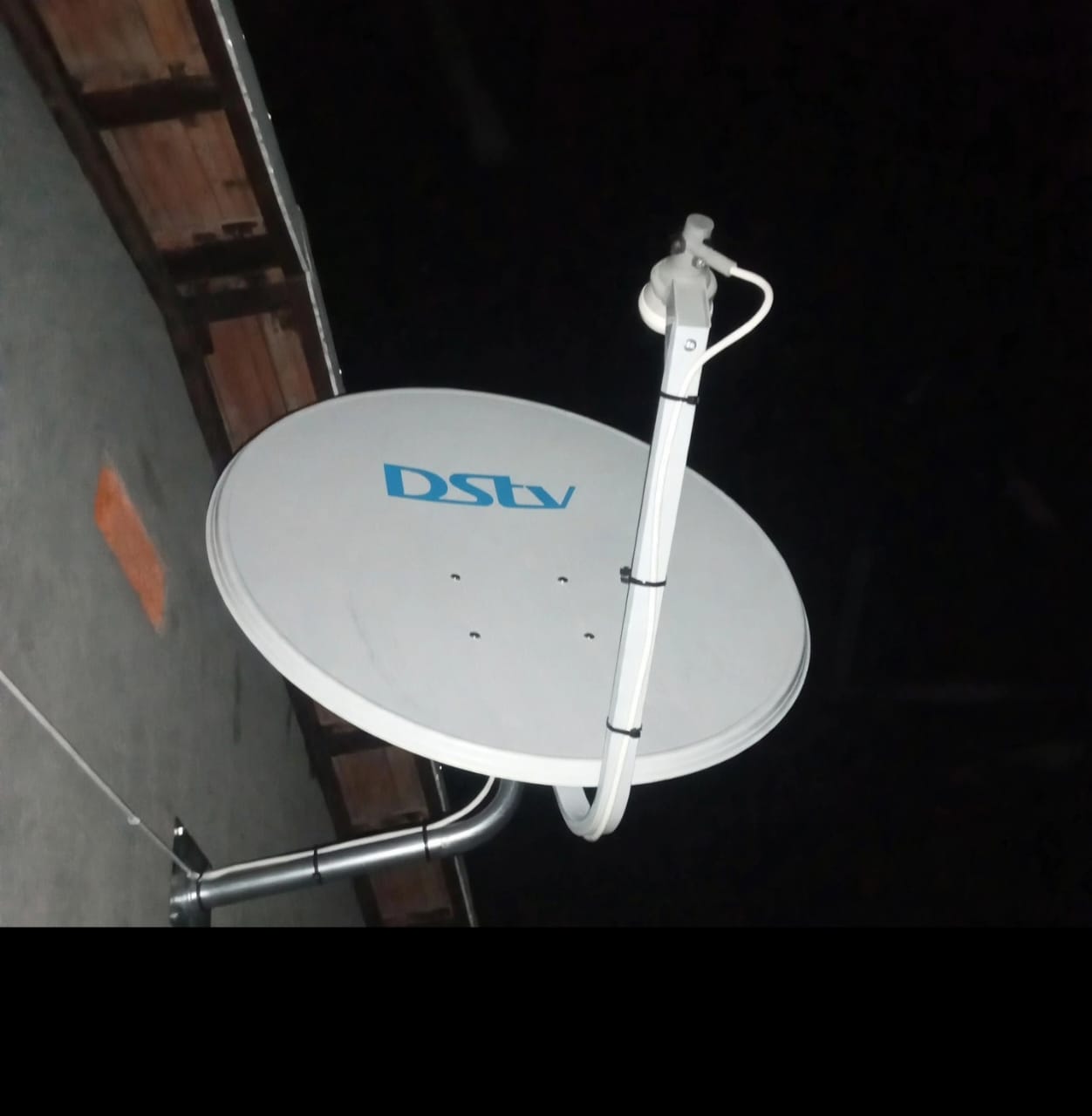 DStv dish installed on a wall bracket at night
